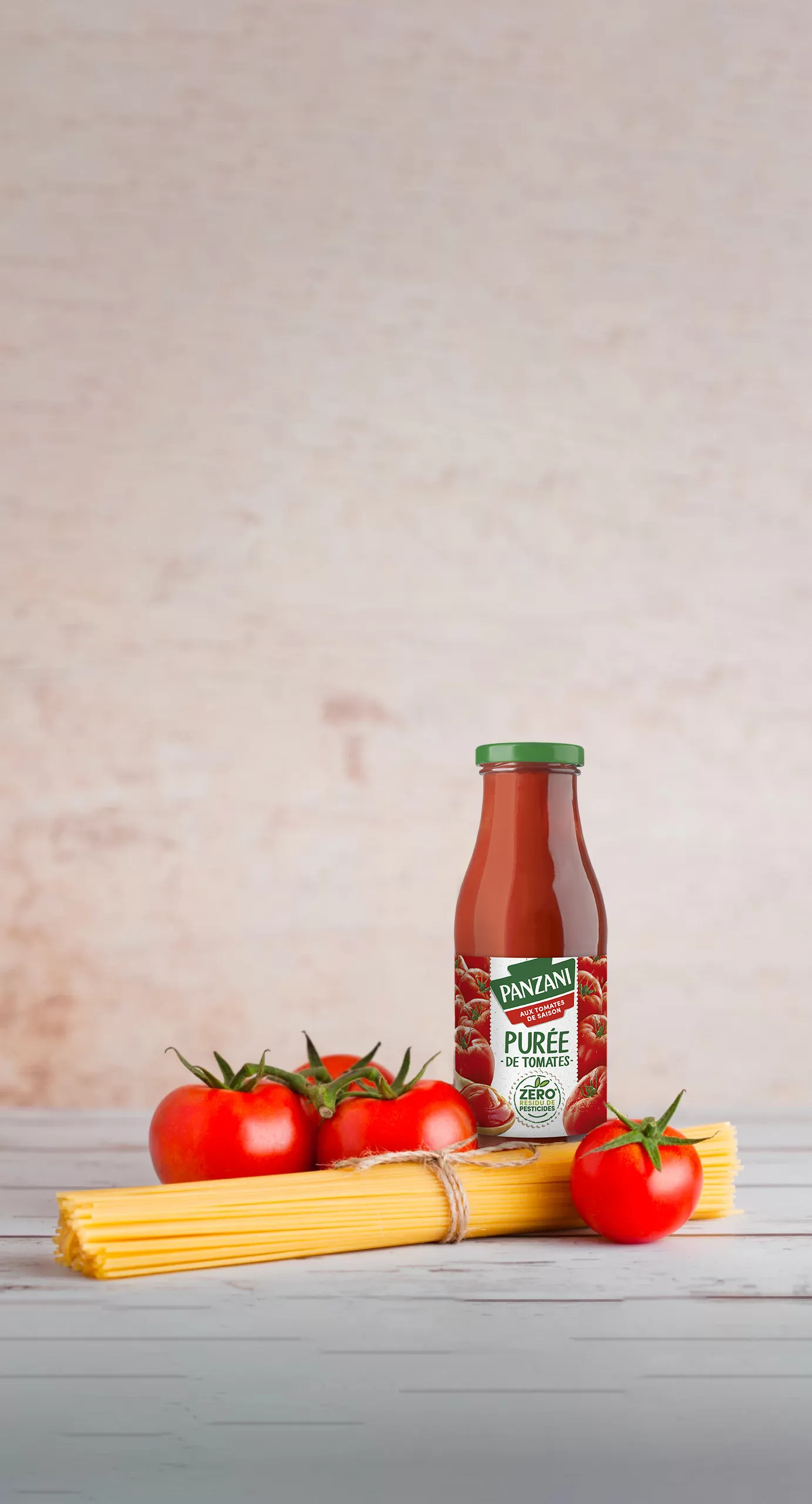 Visuel packshot du produit Purée de tomates Panzani, ambiance culinaire, avec des pâtes et des tomates.